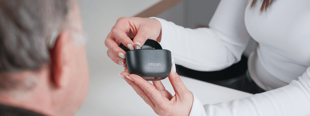 Specialist placing a hearing aid into its charging case